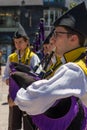 Local bagpipers dressed in traditional clothes play at a city square.