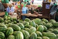 A local burmese man in traditional longyi sleeps next to a huge pile of fresh watermelons at a street market in Myanmar