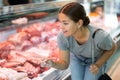 Customer girl looks at glass display case of refrigerator and chooses pork wing ribs Royalty Free Stock Photo