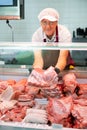 Sales assistant man shows ribbon damp gammon of bacon in meat store