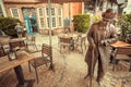 Local cafe, restaurants and sculpture of walking pedestrian on narrow street of old town