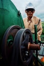 local farmer man extracting rice grains from the plant with a mobile threshing machine next to a river Royalty Free Stock Photo