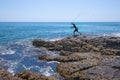 A local fisher man casting his fishing rod on rocks sea coast, shore of the Bay in Asia, Thailand Royalty Free Stock Photo