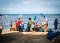 Local fishermen help lift their nets from their boats to unpack and clean the beach in Jomtien, Pattaya, Thailand