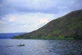 Pandulangan`s rocky hill as background of a small fisherman boat sail in Toba Lake, North Sumatra, Indonesia. Royalty Free Stock Photo