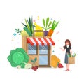 Local fruit and vegetables store building with with a woman. Groceries crates in front of storefront.