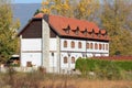 Local hotel built in traditional style with wooden and stone parts surrounded with stone wall and hedge with dry grass and tall Royalty Free Stock Photo