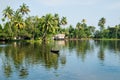 Local Indian man in small boat crossing the river in the Kerala backwaters lined by tropical forest, Alappuzha, Alleppey, India Royalty Free Stock Photo