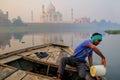 Local man bailing water out of the boat on Yamuna River near Taj Mahal in the morning, Agra, Uttar Pradesh, India