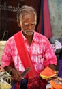 Local man in pink cutting watermelon on street in Yangon