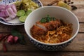 Local northern Thai food Egg noodle curry with fried pork on wood background Royalty Free Stock Photo