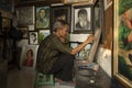 A local painter and cartoonist painting in his small studio and shop.