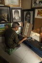 A local painter and cartoonist painting in his small studio and shop.