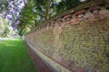 A local park trees with lush foliage along side a brick wall