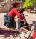 Local Peruvian village women making colorful handmade textiles at textile site in Chinchero, Peru.