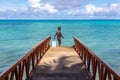 A local Polynesian boy fishing from a jetty pier in a tropical azure turquoise blue lagoon, Tuvalu, Polynesia, Oceania.