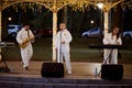 Local pop rock music band performs in gazebo of city public park, energetic outdoor performance