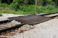 Local railroad crossing made of strong wooden beams held together with rusted screws surrounded with gravel and dense forest