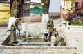 Local resident washing vegetables from a well next to three bronze statues of Naxi women, Lijiang, China