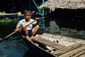 local school boy student paddling home after class at the lake on his canoe in front of the floating stilt house settlement