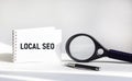 Local SEO written on a notepad, on a white background, next to a magnifier Royalty Free Stock Photo