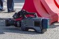 A local television professional video camera is on pavement between reports. Front view