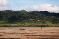 Local Thai guy with fishing boat on muddy land of Tung Yee Peng, Koh Lanta island, Krabi, Thailand