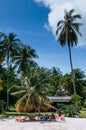 Local Thai tourist sitting on colourful beach beds under coconut