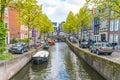 Local and tourist walking on a small Amsterdam Canal in spring in the Jordaan area with boats, bikes and cars Royalty Free Stock Photo