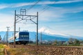 A local train of JR Izuhakone Tetsudo-Sunzu Line traveling through the countryside on a sunny winter day and Mt. Fuji in Mishima,