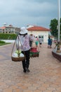 Local vendor carrying street foods on a shoulder mounted rack.