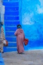 A local walks in the alley in Chefchaouen, Morocco.