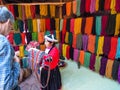 Local woman dressed in traditional clothing in front of dyed alpaca wool in Awana Kancha. Royalty Free Stock Photo