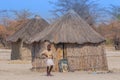 Local woman near a typical thatched roof African round hut in Botswana