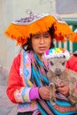 Local woman in traditional dress holding lamb in the street of C