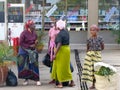 Local women wait at the bus stop and chat after coming from the daily market in the town center of Moshi