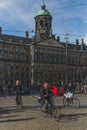 Locals biking past Royal Palace Amsterdam