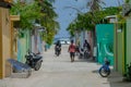 Locals walk and ride a scooter down a street leading to port of an exotic island Royalty Free Stock Photo