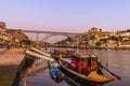 Typical boats and Dom Luis I bridge in Porto at dusk in Portugal