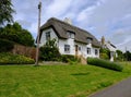 View of a traditional English cottage and thatched roof with a well painted lawn area.