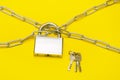 lock on a chain on a yellow background, a bunch of keys lies nearby