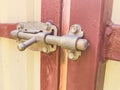 Lock on the door in the old house. latch from other people`s entry. homemade deadbolt on the door and gate of red color. concrete Royalty Free Stock Photo