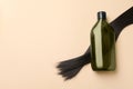 Lock of hair and shampoo bottle on beige background, flat lay. Space for text Royalty Free Stock Photo