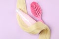 Lock of hair, shampoo and hairbrush on purple background Royalty Free Stock Photo