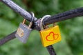 The lock, a symbol of love and loyalty, hangs on iron bars. Red Hearts are painted on a yellow lock. A piece of iron tree with