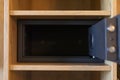 A lockable safe is positioned in an open wooden cabinet, showcasing its depth and design. Ideal for securing important items in a Royalty Free Stock Photo