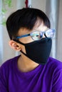 Lockdown and school closures. School boy wearing glasses showing outdoor reflection light with face mask feeling bored and