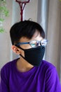 Lockdown and school closures. School boy wearing glasses showing outdoor reflection light with face mask feeling bored and