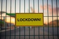 Lockdown sign on a fence with blured city view on a background at sunset