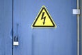 Locked electric old metal door with attention sign on the blue wall of transformer substation. Closed overhead lock and high Royalty Free Stock Photo